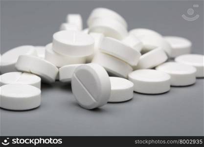 Heap of white round pills medical. Heap of white round pills medical on a gray background