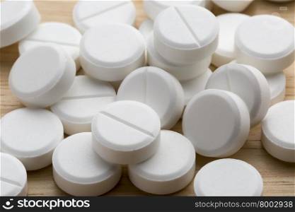 Heap of white round pills on a gray background. Heap of white round tablets on a wooden background