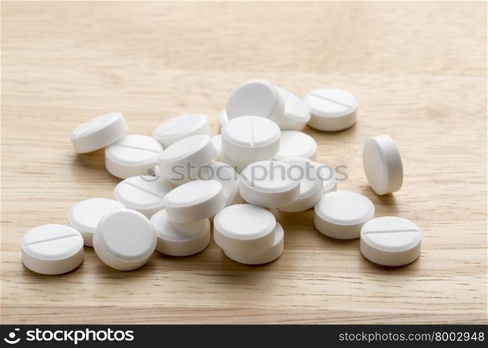 Heap of white round pills on a gray background. Heap of white round tablets on a wooden background