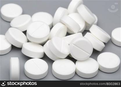 Heap of white round tablets medical. Heap of white round tablets on a gray background