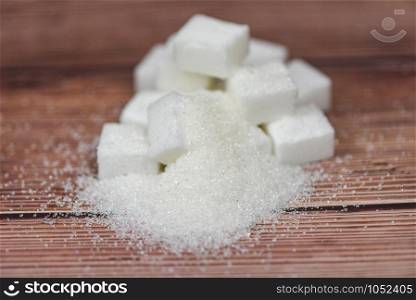 Heap of white sugar on wooden table background / sugar cubes