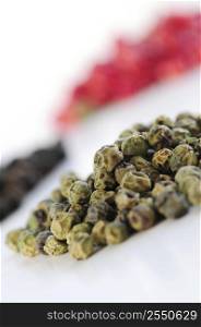 Heaps of assorted peppercorns on white background