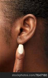 hearing, health and beauty concept - close up of african american woman&rsquo;s finger pointing to her ear. close up of african american woman&rsquo;s ear