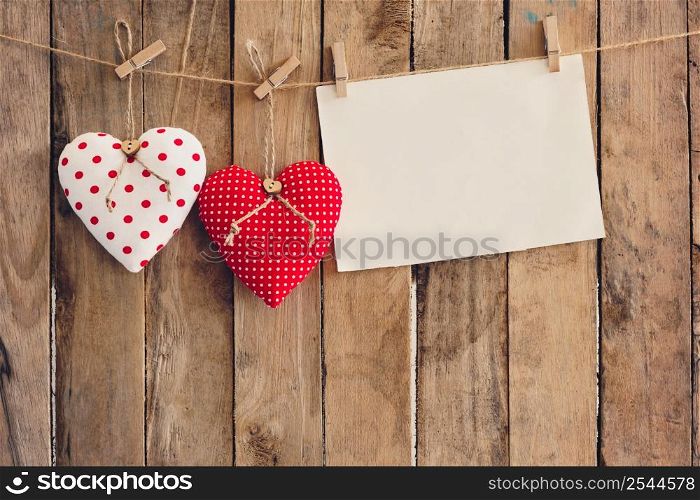 Heart and empty paper hanging on wood background with copy space.