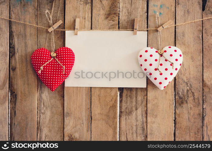 Heart and empty paper hanging on wood background with copy space.