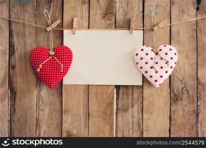 Heart and empty paper hanging on wood background with copy space.
