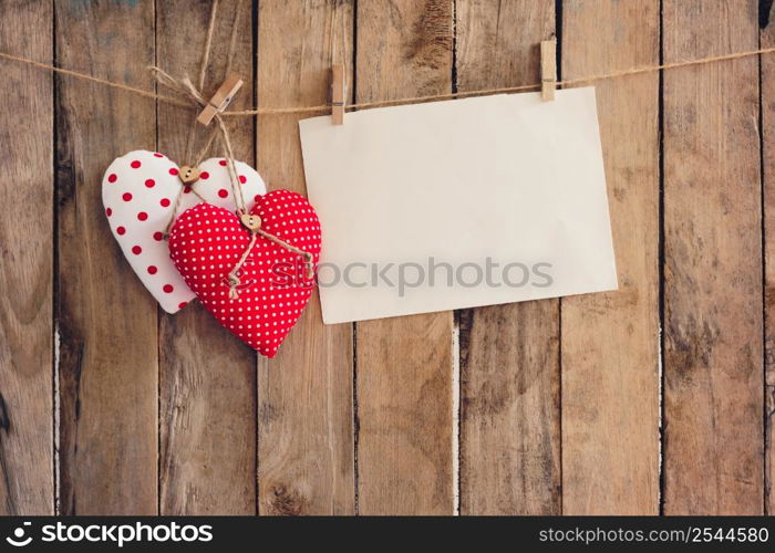 Heart and empty paper hanging on wood background with copy space.