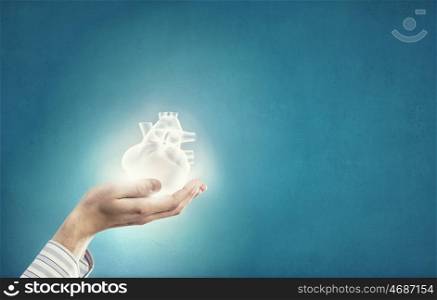 Heart care. Close up of human hands holding human heart