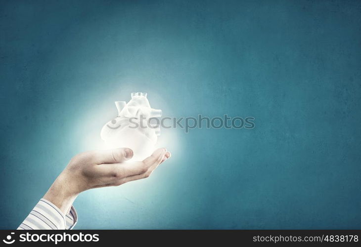 Heart care. Close up of human hands holding human heart