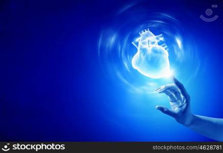 Heart care. Close up of person hand touching human heart on blue background
