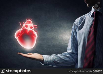 Heart care concept. Close up of man hand holding human heart
