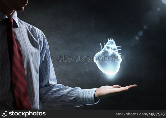 Heart care concept. Close up of man hand holding human heart