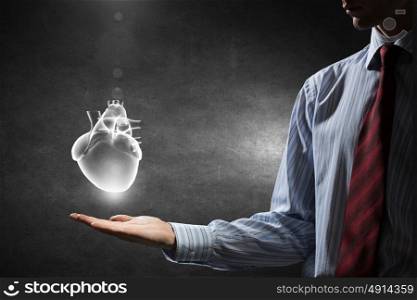 Heart care concept. Close up of man hand holding human heart