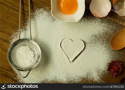 Heart drawn in flour surrounded by ingredients for cooking