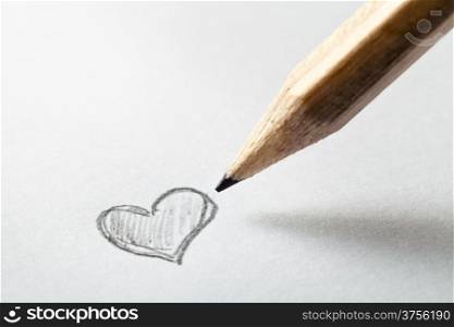 Heart drawn in pencil on a paper sheet, macro shot with copy space