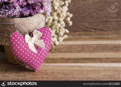 Heart fabric and dry flowers on wooden background