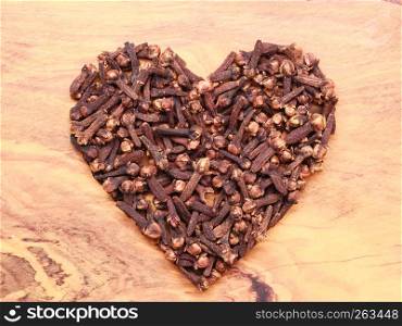 Heart form made from spice cloves on wooden background
