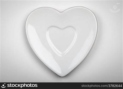 Heart form white plate on gray background. Top view