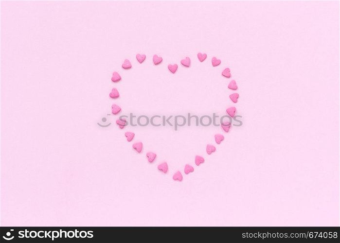 Heart from pink confectionery sprinkles in heart shape located in the center on pastel pink background. Concept Valentine's card. Top view Copy space for text.. Pink confectionery sprinkles in heart shape on pastel pink background. Concept Valentine's card. Top view Copy space for text