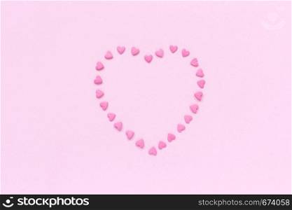 Heart from pink confectionery sprinkles in heart shape located in the center on pastel pink background. Concept Valentine's card. Top view Copy space for text.. Pink confectionery sprinkles in heart shape on pastel pink background. Concept Valentine's card. Top view Copy space for text