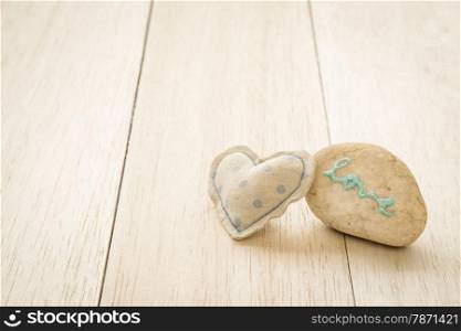 Heart handmade craft from blue polka dot cotton cloth with glitter love word on pebble place on wood background, anniversary and valentine&rsquo;s day symbol