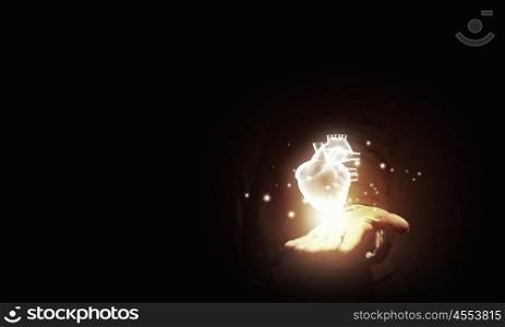 Heart in hand. Close up of businessman holding digital glowing heart in palm