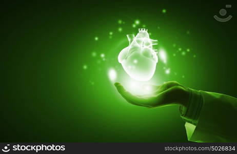 Heart in hand. Close up of businessman holding digital glowing heart in palm