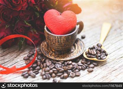 Heart in wooden coffee cup with coffee beans romantic love valentines day and red rose flower on wood background / love coffee concept