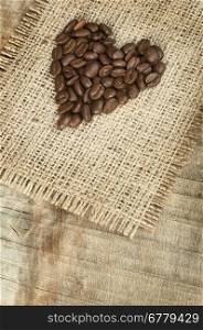 Heart made a??a??of coffee beans on wooden board