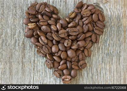Heart made from coffee beans on wooden background