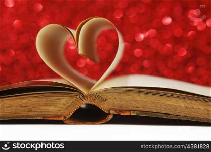 Heart made of blank pages inside a book on glitter background