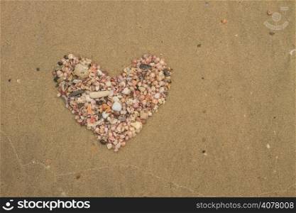 Heart made of sea shells lying on a beach sand in summer