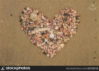 Heart made of sea shells lying on a beach sand in summer