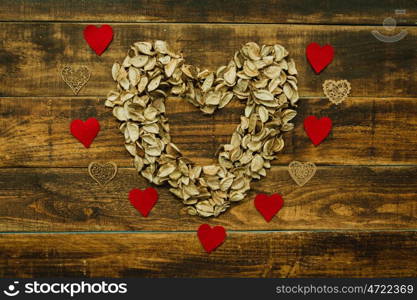 Heart maked with dry petals on a wooden background