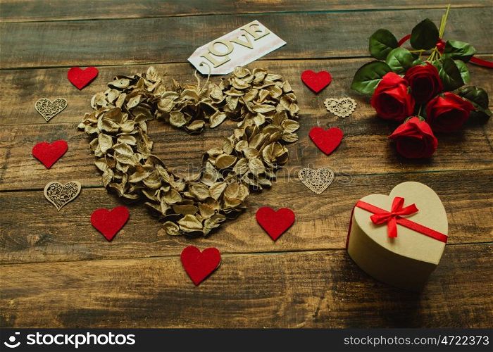 Heart maked with dry petals on a wooden background
