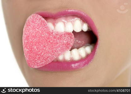 Heart shape candy on beautiful woman macro mouth