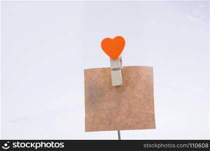 Heart shape clothespin attached to a note paper on a white background