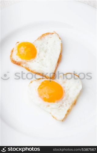 Heart shape fried eggs on the white plate
