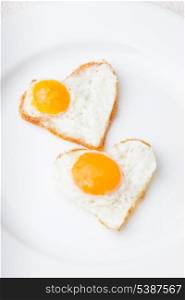 Heart shape fried eggs on the white plate