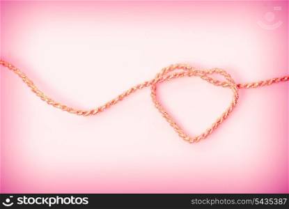 Heart shape from gold rope on pink background. Love postcard