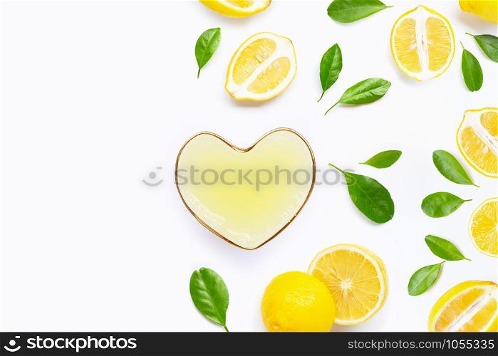 Heart shape glass of freshly squeezed lemon juice with fresh lemon on white background. Copy space