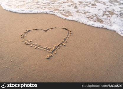 Heart shape hand writing on sandy beach