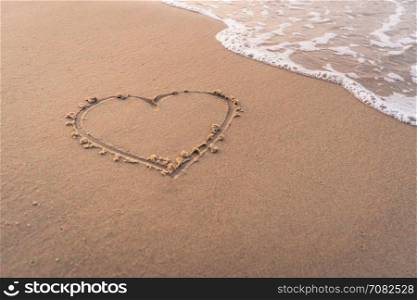 Heart shape hand writing on sandy beach