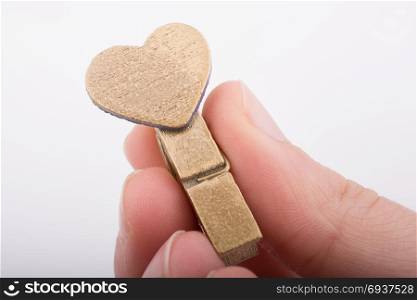 Heart shape icon attached to a clothespin in hand