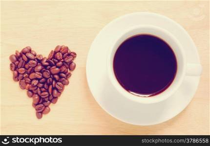 Heart shape made from coffee beans with a cup of coffee, retro filter effect