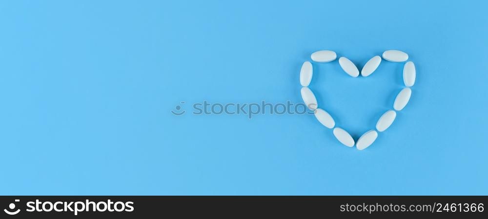 Heart shape made from white tablets on a blue backdrop with copy space.. Heart shape made from white tablets on blue backdrop with copy space.
