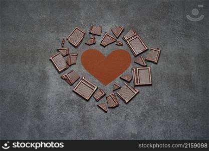 Heart shape made of grinded coffee or cocoa powder and pieces of chocolate bar on concrete background.. Heart shape made of grinded coffee or cocoa powder and pieces of chocolate bar on concrete background
