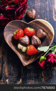 heart shape plate with strawberries and chocolate on wooden table - Valentine&rsquo;s day and love concept