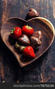 heart shape plate with strawberries and chocolate on wooden table - Valentine&rsquo;s day and love concept