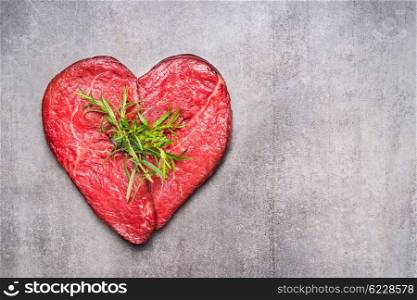 Heart shape raw meat with herbs and text on gray concrete background , top view, horizontal